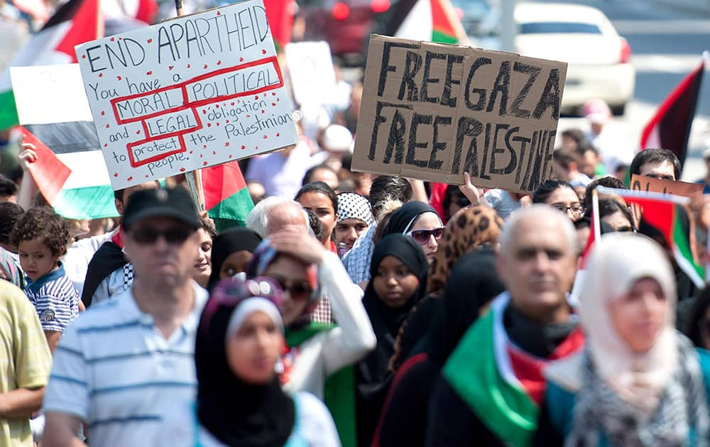 People wave signs as they march along Elgin Street in Ottawa, Ontario, during a protest in response to the crisis in Gaza.