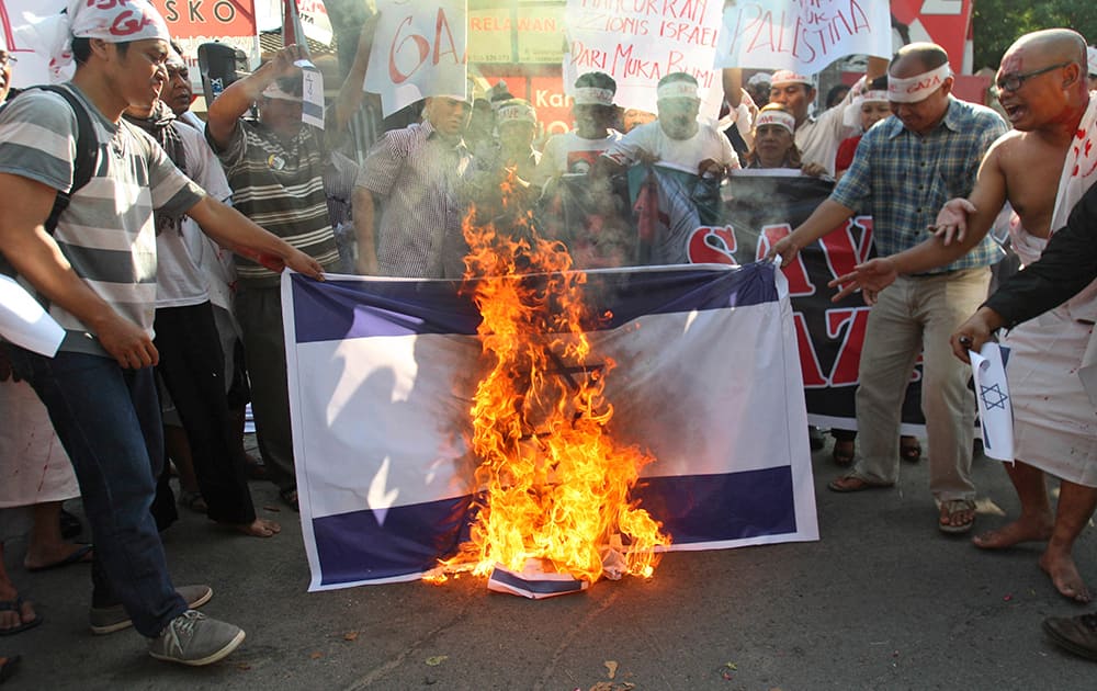 Indonesian Muslim protesters burn an Israeli flag during a rally against Israeli attack on Gaza in Surabaya, East Java, Indonesia.