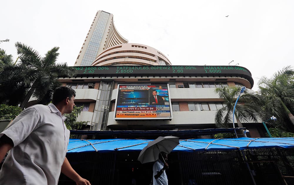 A man looks at the display screen on the facade of the Bombay stock exchange (BSE) in Mumbai. India`s new government introduced a reform-minded budget Thursday, vowing to lift economic growth to rates of 7-8 percent by promoting manufacturing and infrastructure and overhauling populist subsidies. 