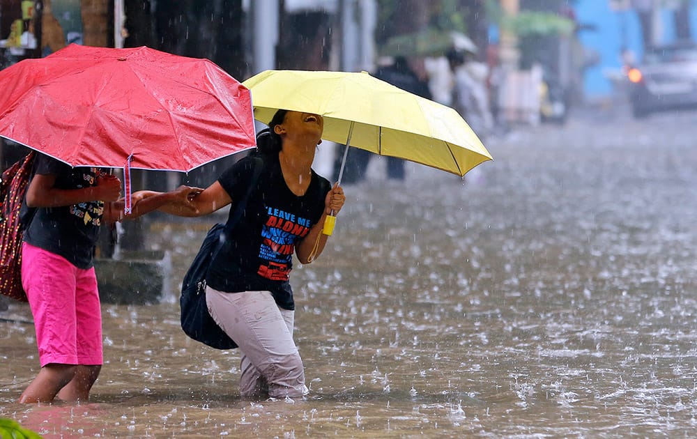 A girl laughs as she wades through knee-deep water in the rain in Mumbai.