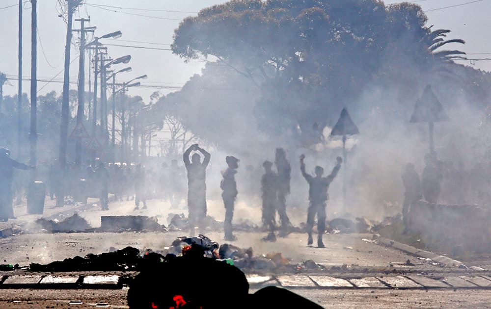 An electric pole and rubbish bins burns in the foreground, as Langa township residents protest, on the outskirts of the city of Cape Town, South Africa.