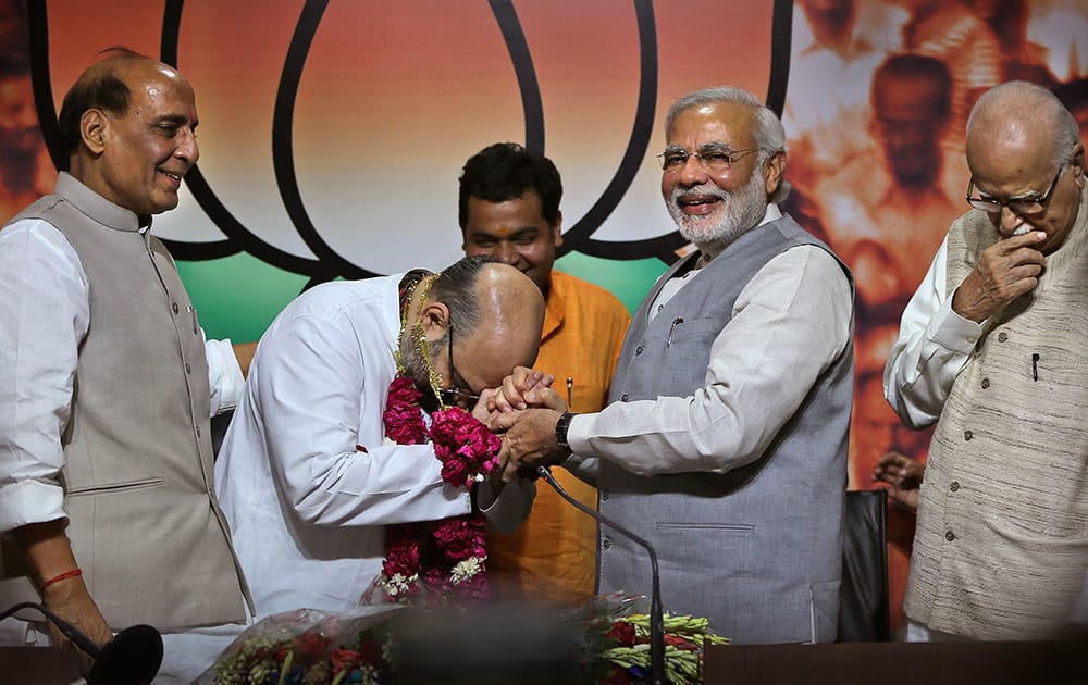 Prime Minister Narendra Modi, greets newly appointed Bharatiya Janata party or BJP president Amit Shah, as outgoing party president Rajnath Singh, and BJP senior leader L.K.Advani watch, at the party`s headquarters in New Delhi.