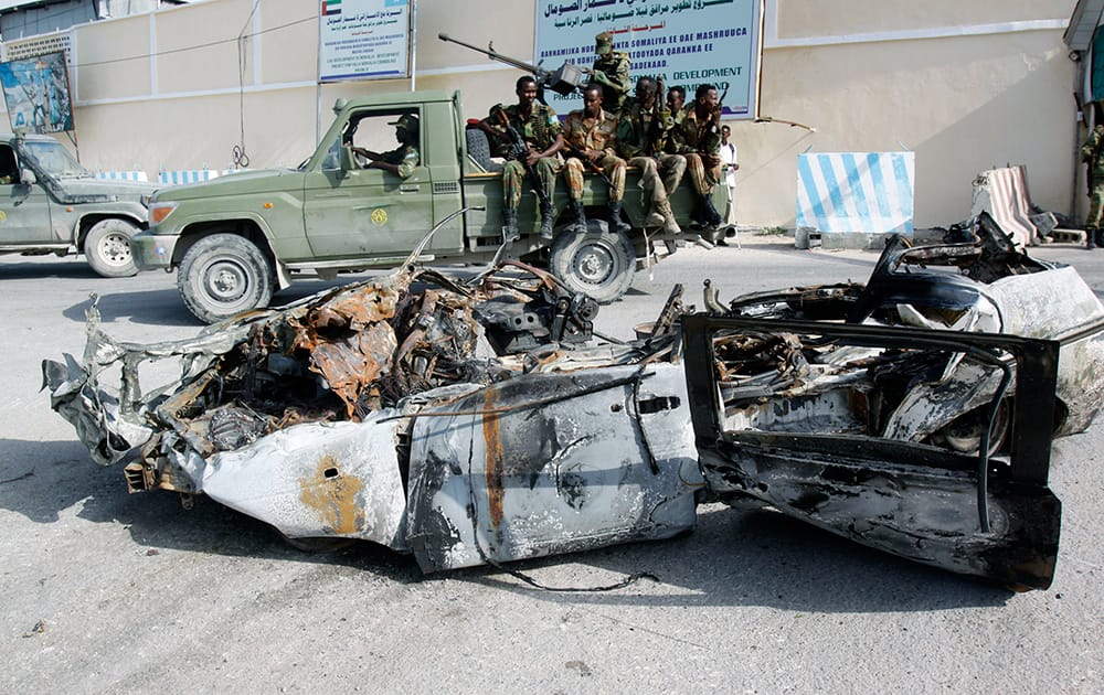 Somali soldiers sit on a pickup truck near the wreckage of a car bomb that was detonated at the main gate of the presidential palace in Mogadishu, Somalia.