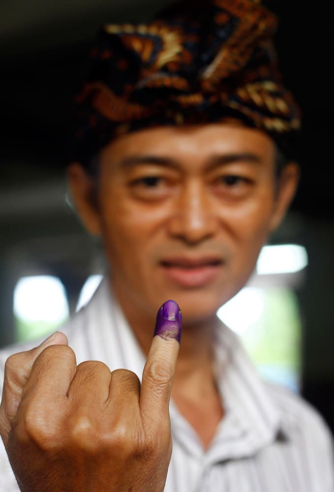 A voter shows off his finger marked with indelible ink after casting his ballot in the presidential election in Bali, Indonesia.