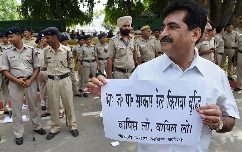 A Congress worker displays a placard during a protest against the Rail Budget outside the residence of Railway Minister DV Sadananda Gowda in New Delhi.