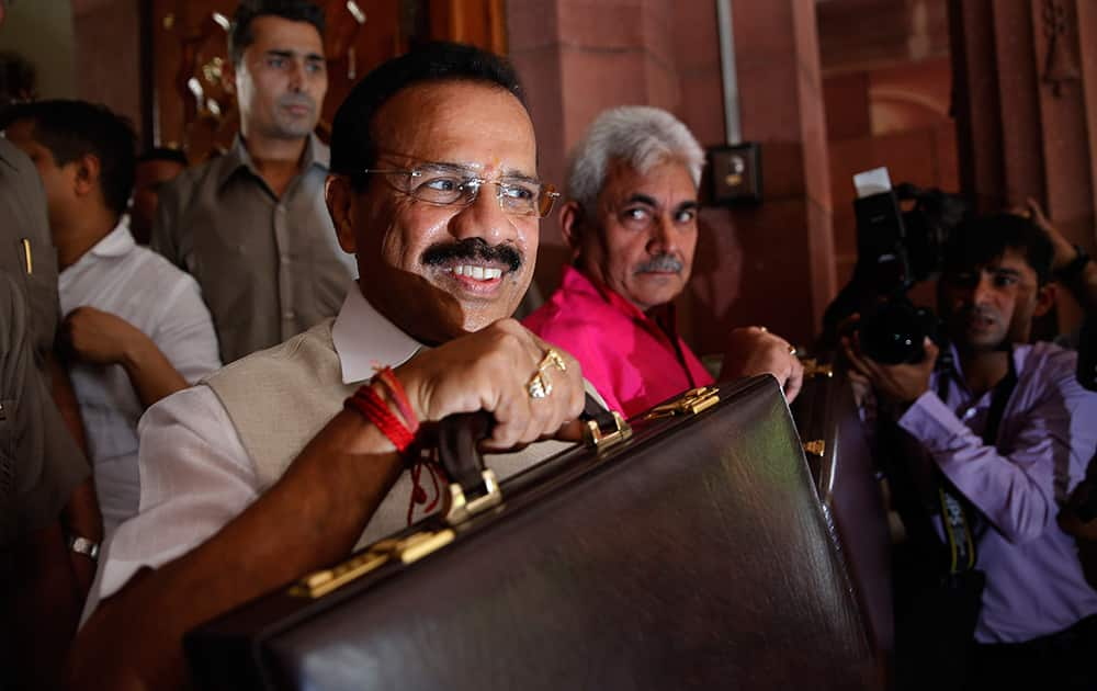 Railway Minister Sadananda Gowda shows the briefcase containing Rail budget for the year 2014 to media persons as he arrives in the parliament house to present the budget, as junior minister for Railways Manoj Sinha watches, in New Delhi.