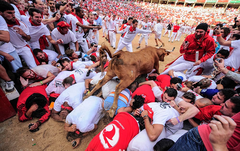 A cow jumps over revelers who wait for the animal on the bull ring, at the San Fermin festival, in Pamplona, Spain.