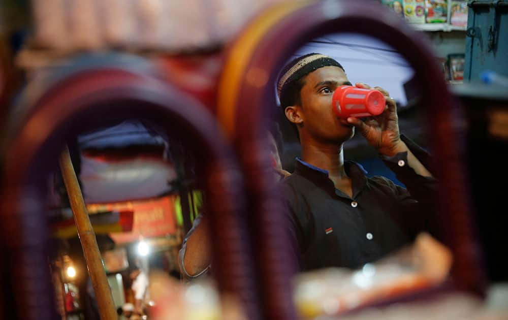 An Indian Muslim taking a drink is reflected in mirrors at a shop as he breaks his fast during the Islamic holy month of Ramadan in Allahabad.