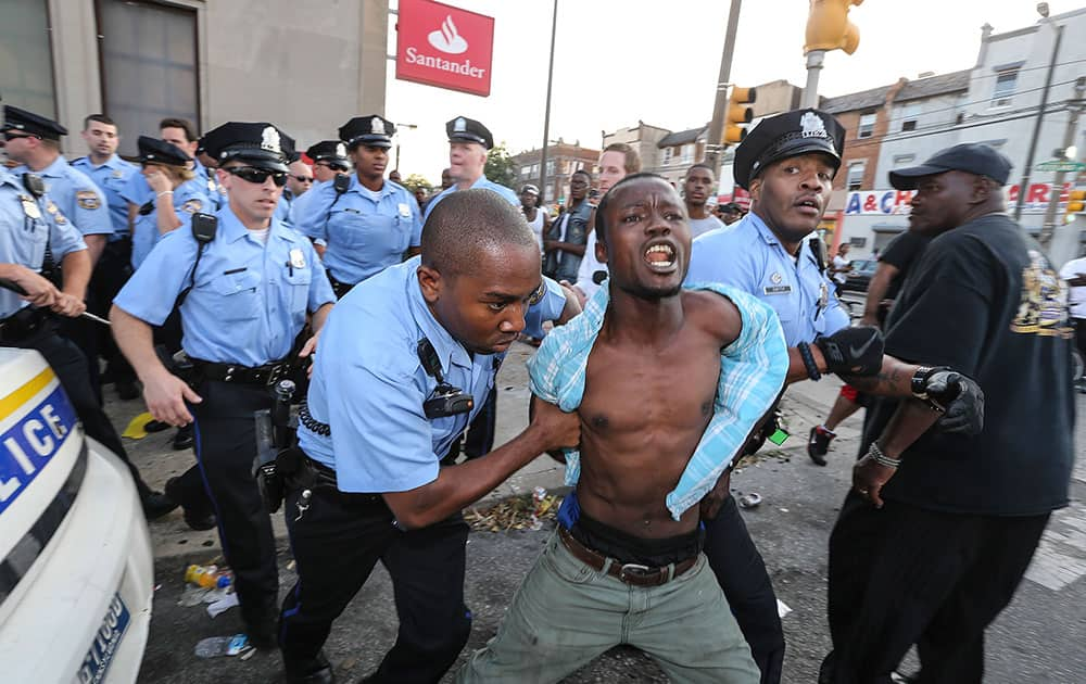 Police officers arrest a protester, Monday, July 7, 2014, at the fire station a block away from a fire scene that claimed 4 young children early Saturday morning in Philadelphia.