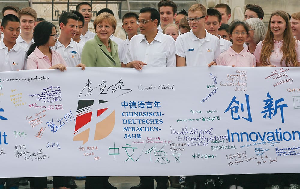 German Chancellor Angela Merkel and Chinese Premier Li Keqiang join Chinese and German high school students to hold a symbolic banner for an education and language exchange program during her visit to the Temple of Heaven in Beijing, China.