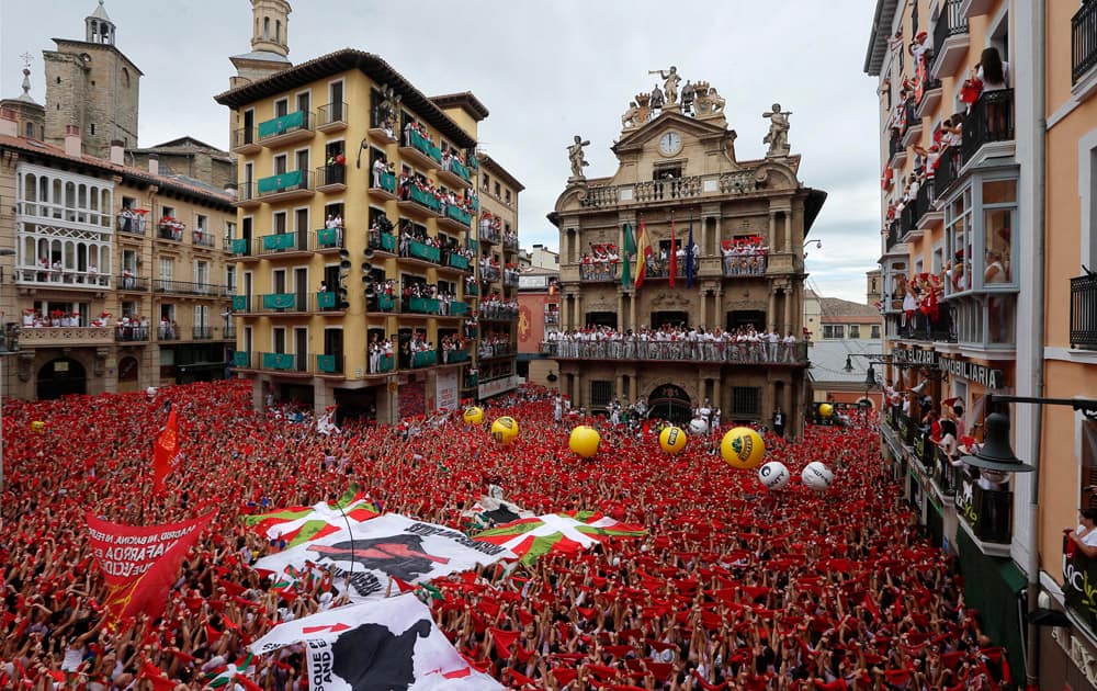 Revelers hold up traditional red neckties during the launch of the `Chupinazo` rocket, to celebrate the official opening of the 2014 San Fermin fiestas, in Pamplona, Spain.