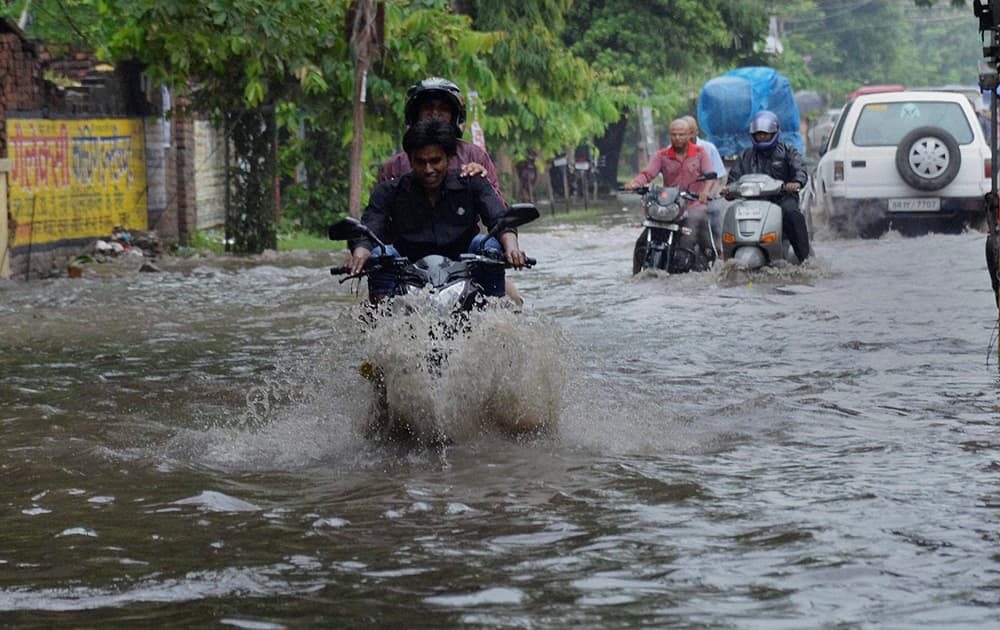 People wade through a waterlogged road after heavy rains in Patna.