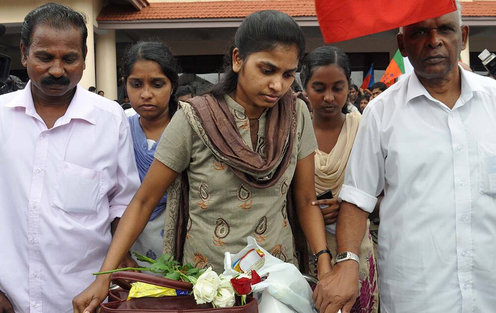 An Indian nurse, center, who was among 46 nurses stranded in territory held by Islamic extremists in Iraq, walks with a baggage trolley upon arrival at the airport in Kochi.