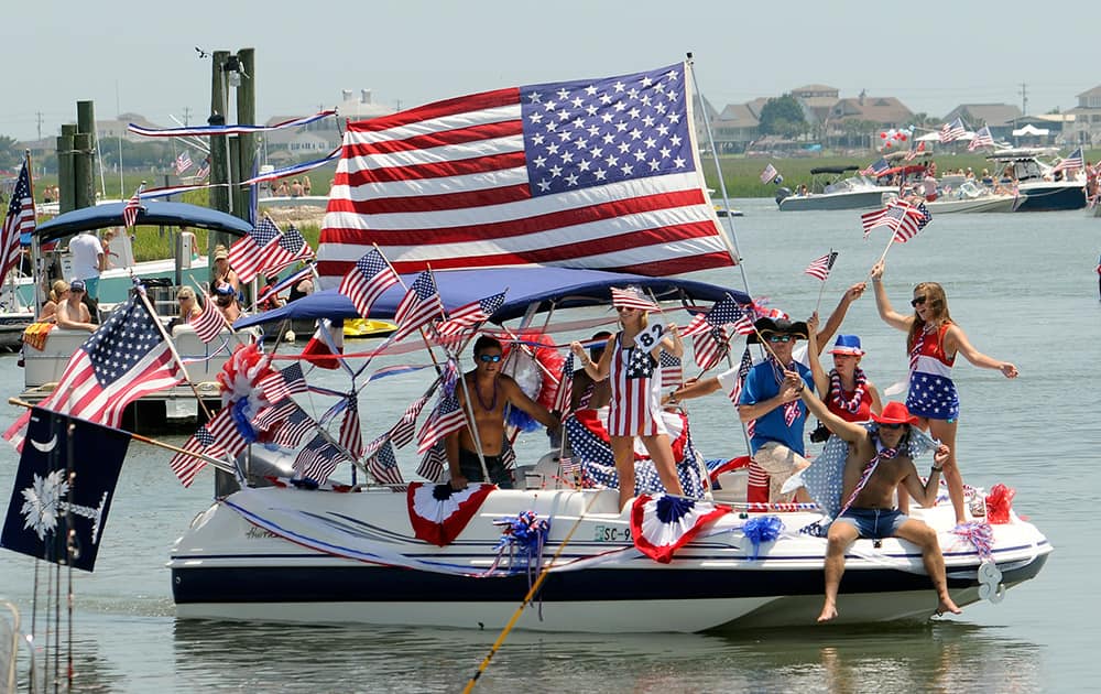 People wave from a boat adorned with bunting and US flags during the 31st annual Murrells Inlet Fourth of July Boat Parade.