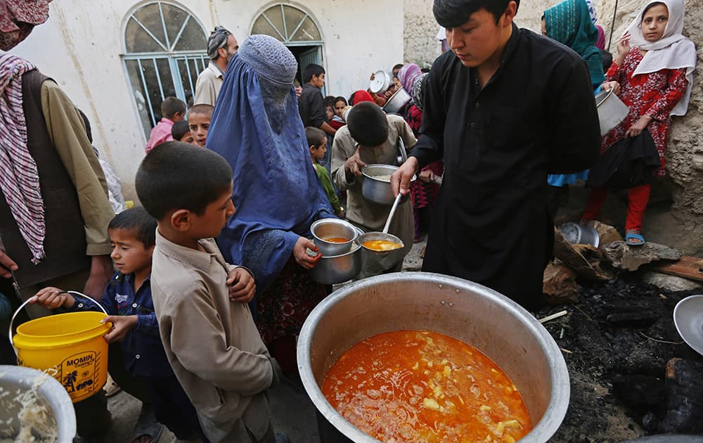 Afghan villagers receive free food donated by other villagers as they prepare to break their fast during the holy month of Ramadan in Kabul, Afghanistan.