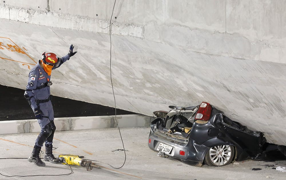 A policeman looks at a car crushed underneath a collapsed bridge in Belo Horizonte, Brazil.