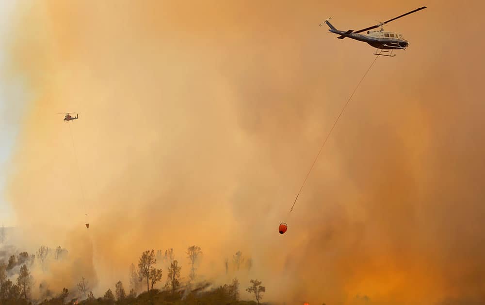 Private hire helicopters make water drops on the Butts Fire above Snell Valley as the afternoon winds kicked up, near Middletown, Calif. 