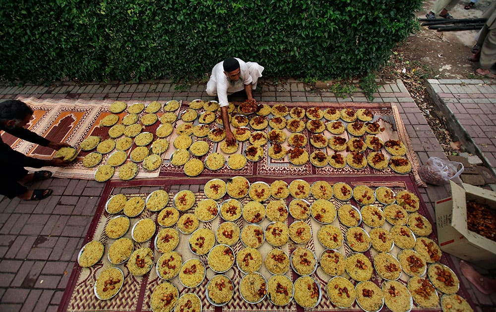 A Pakistani arranges plates of food prepared and ready for free distribution for the Iftar meal that breaks the day`s fast at sunset, during the Islamic holy month of Ramadan outside a mosque in Islamabad.