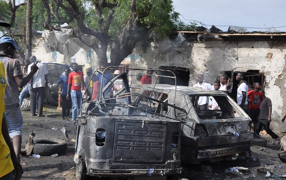 People look at damaged vehicles, at the scene of a car bomb explosion, at the central market, in Maiduguri, Nigeria.