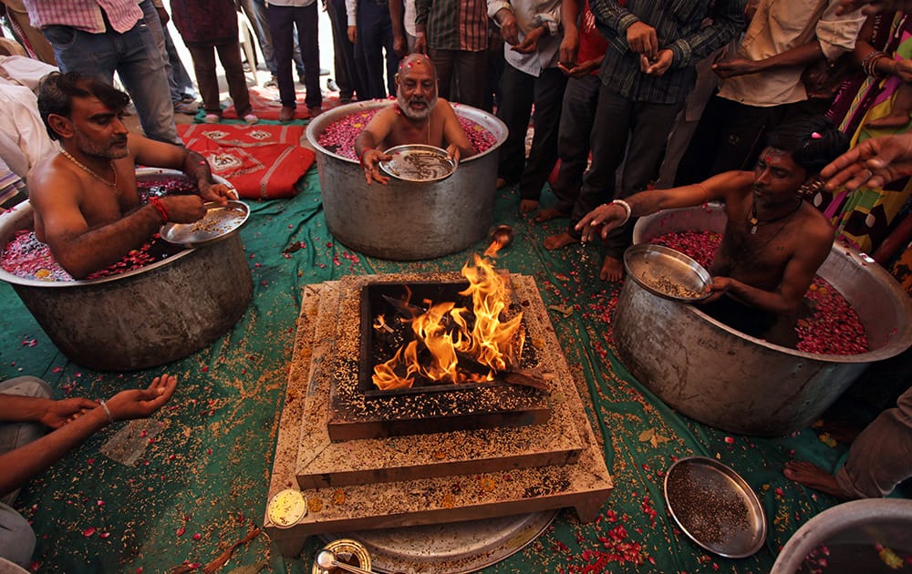 People sit in vessels filled with water and perform Hindu rituals to appease the rain god in Ahmadabad.