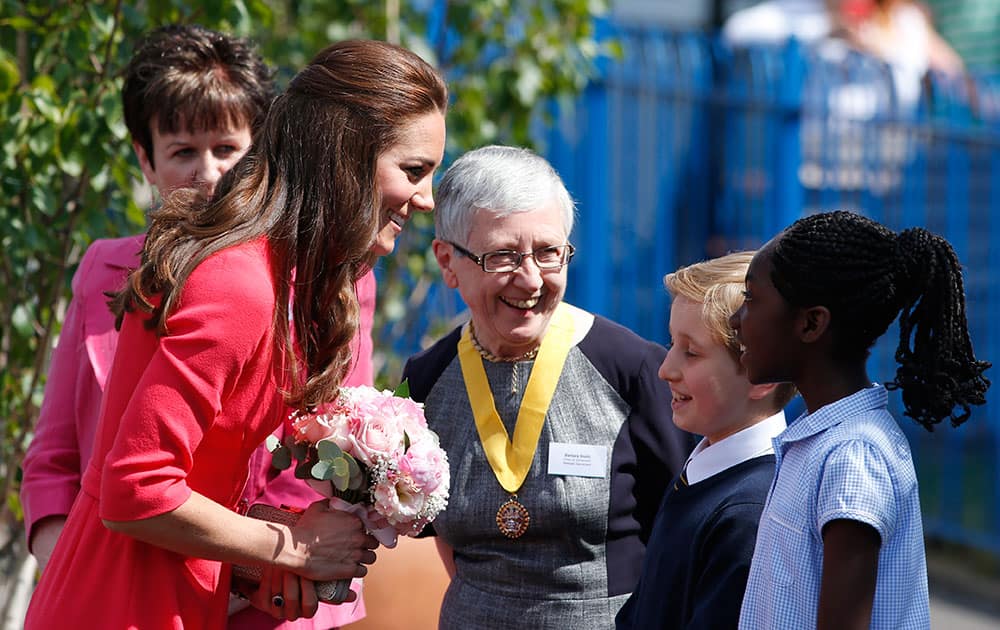 Britain`s Kate, the Duchess of Cambridge, left, talks to pupils as she arrives at the Blessed Sacrament School in London.