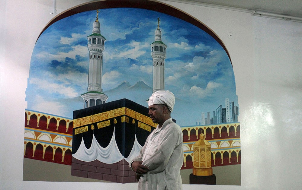 A Pakistani offers afternoon prayers in front of a mural depicting the Kaaba and the Grand Mosque in Mecca, Saudi Arabia, during the Muslim holy month of Ramadan, at a mosque in Lahore, Pakistan.