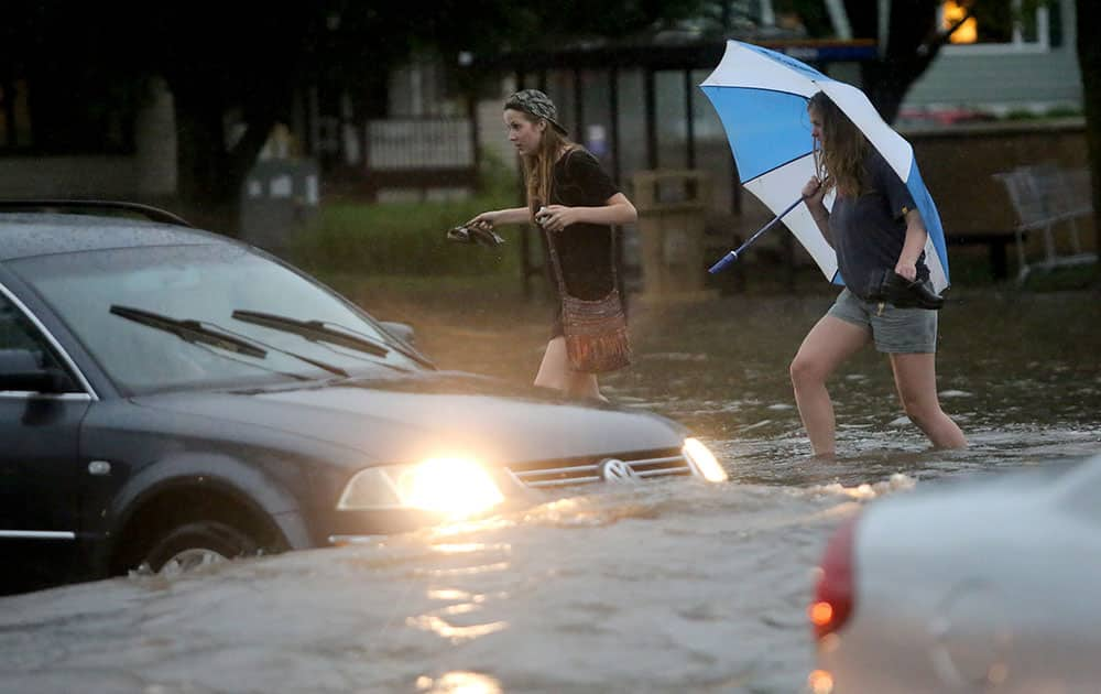 Pedestrians and motorists attempt to navigate the flooded intersection of University Boulevard and North Midvale Road in Madison, Wis., after heavy rain moved through the area.