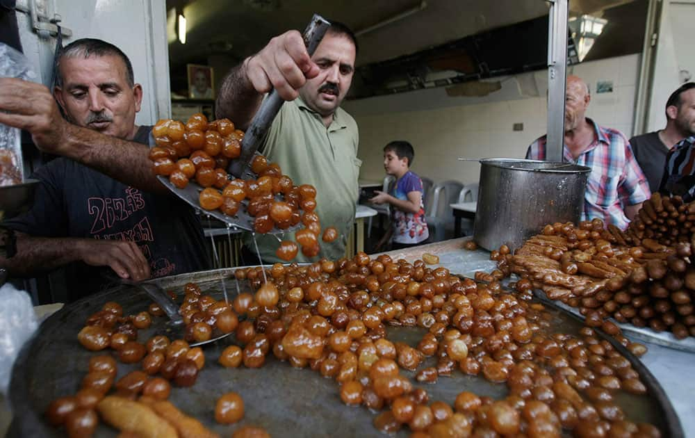 Palestinian vendors sells fried dough ball sweets locally called `awwamaat` at a shop on the first day of the Muslim holy month of Ramadan in the West Bank city of Nablus