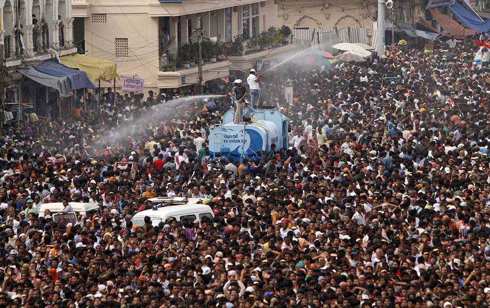 Volunteers spray water on devotees during the annual Hindu festival ‘Rath Yatra’ or chariot procession in Puri, Orissa state.