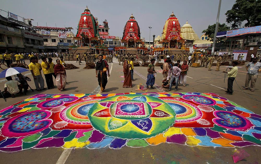 People stand near a design made of colored powder on the premises of the temple of Hindu god Jagannath during the annual Hindu festival ‘Rath Yatra’ or chariot procession in Puri, Orissa state.