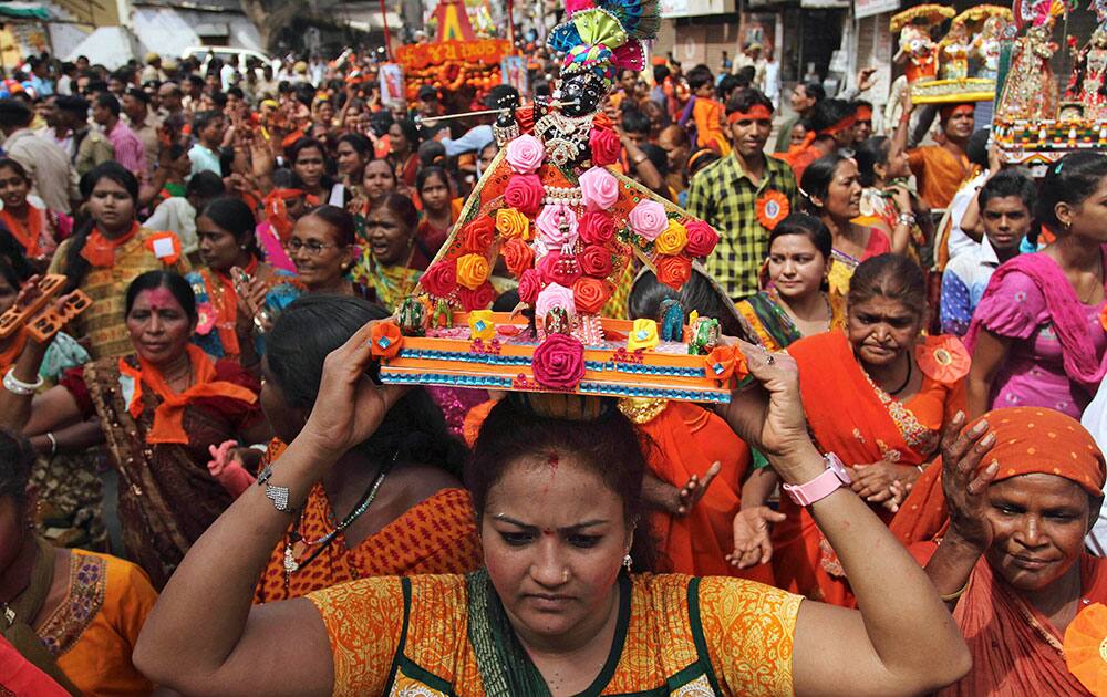 A woman carries an idol of Lord Krishna during the annual Hindu festival ‘Rath Yatra’ or chariot procession in Ahmedabad.