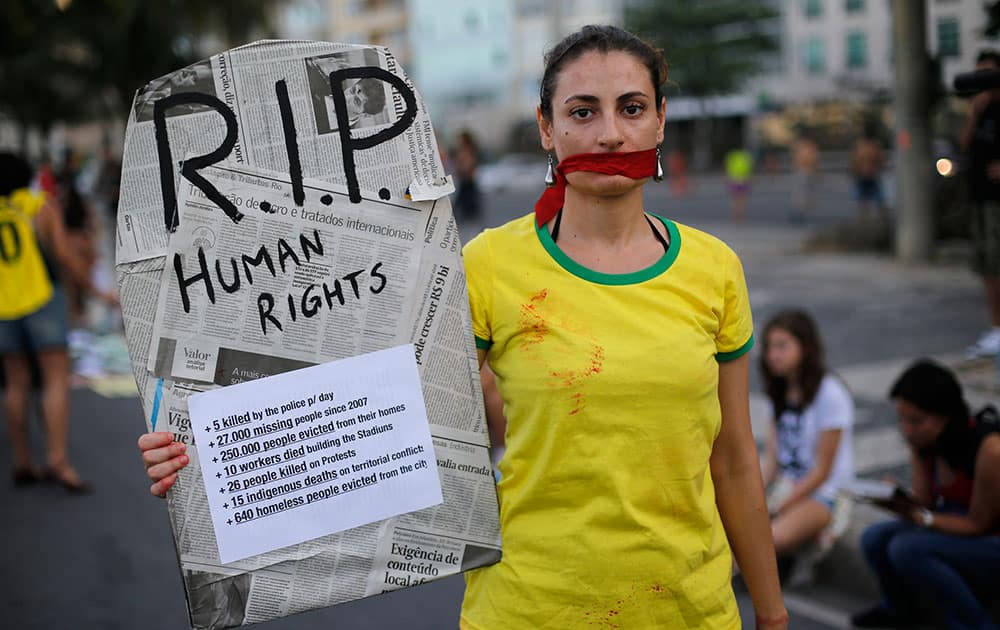 A woman wears a t-shirt with the Brazil national colors while holding a sign with the form of a coffin that reads, `R.I.P Human Rights` during a protest against the money spent on the 2014 soccer World Cup and demanding better public services, at Copacabana beach in Rio de Janeiro, Brazil.