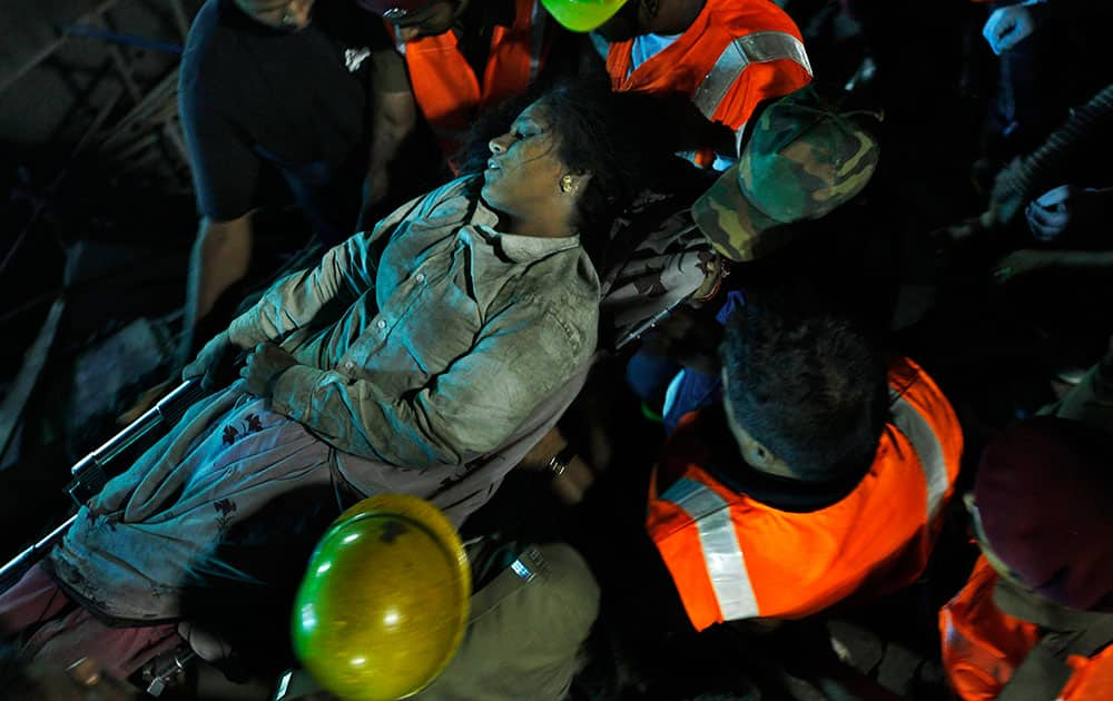 Rescuers carry an injured woman worker pulled out from the rubble of a building that collapsed on the outskirts of Chennai, India.