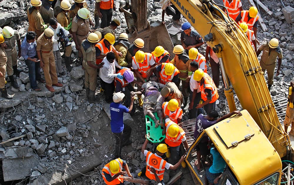 Rescuers carry the body of a woman, one of the workers killed from site of a building that collapsed on the outskirts of Chennai, India.