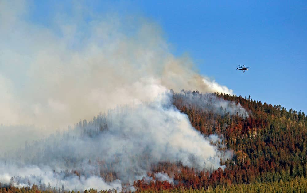 A helicopter hovers above the San Juan Fire, in Vernon, Ariz. Emergency crews have set up a shelter for evacuees of a wildfire in northeastern Arizona`s White Mountains that has charred more than 8 square miles. 