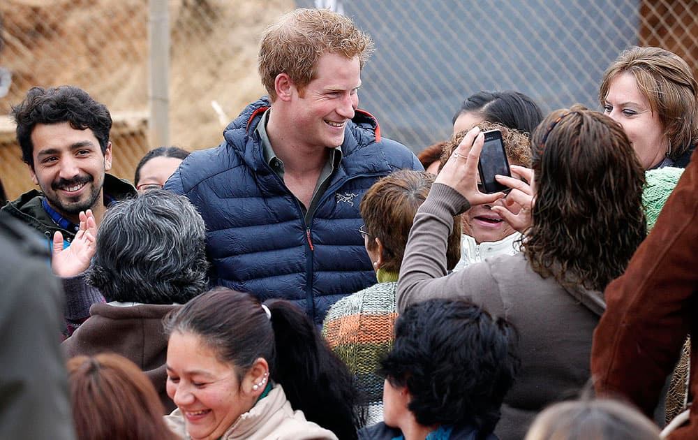 Britain`s Prince Harry poses for pictures as he visits families living in temporary housing in the El Vergel slum after they lost their homes to an April forest fire in Valparaiso, Chile.