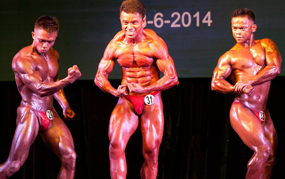 Bodybuilders pose during contest at Myanmar Convention Centre in Yangon, Myanmar.