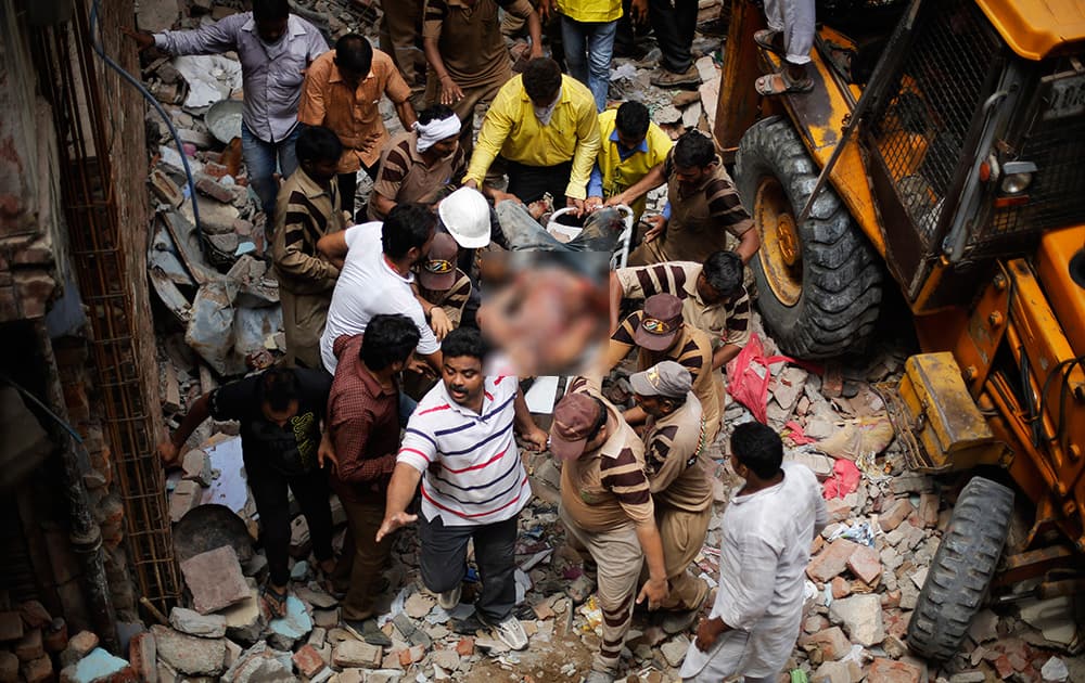 Rescue workers carry the body of a victim out of the debris of a building that collapsed in New Delhi.