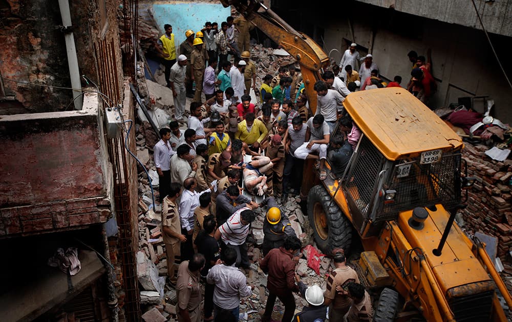 Rescue workers carry the body of a victim out of the debris of a building that collapsed in New Delhi.