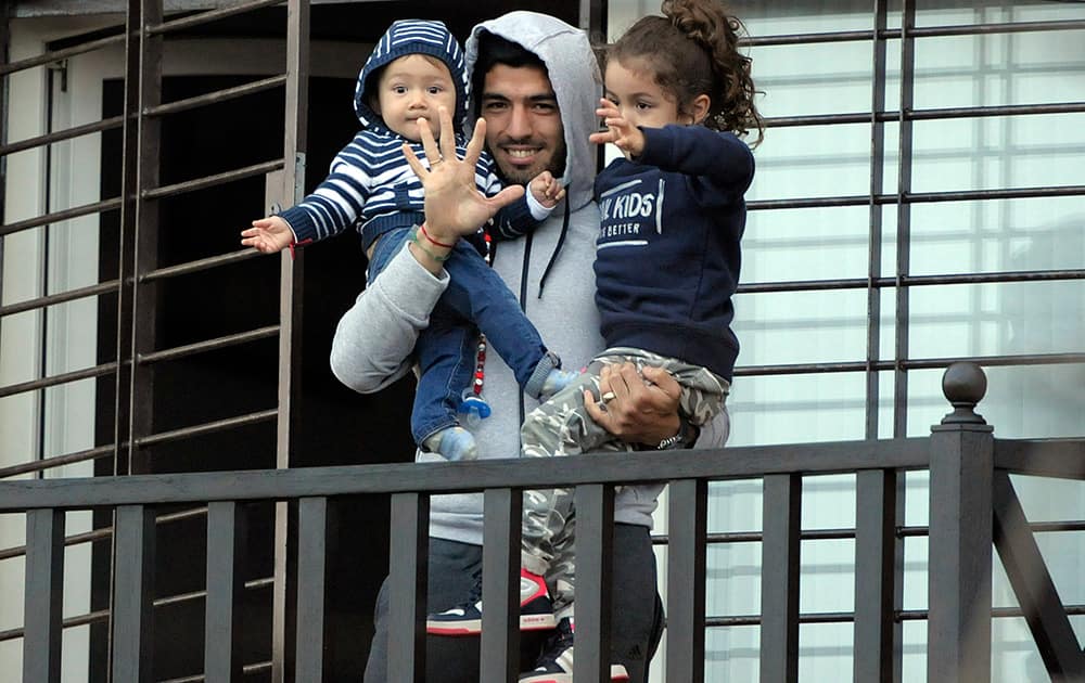 Uruguay`s soccer player Luis Suarez holds his children as he greets fans from their home`s balcony on the outskirts of Montevideo, Uruguay.