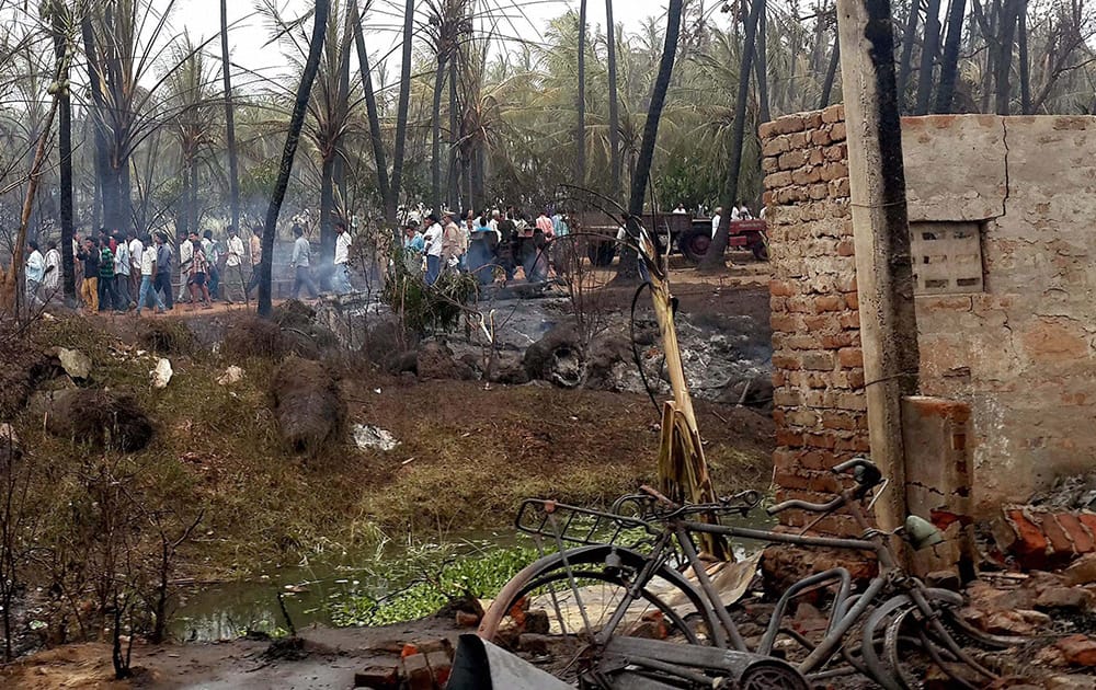 People standing near coconut trees burnt in GAIL gas leak fire in Nagaram village near Rajahmundry in East Godavari district of Andhra.