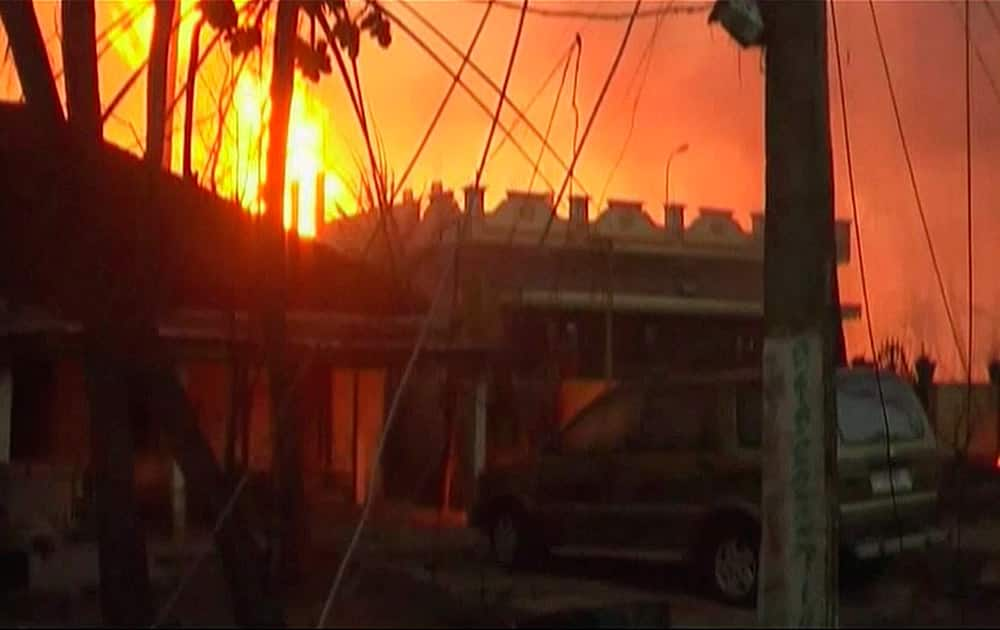 Flames rise in the background of houses after a state-owned gas pipeline exploded in Nagaram village, in the southern Indian state of Andhra Pradesh.