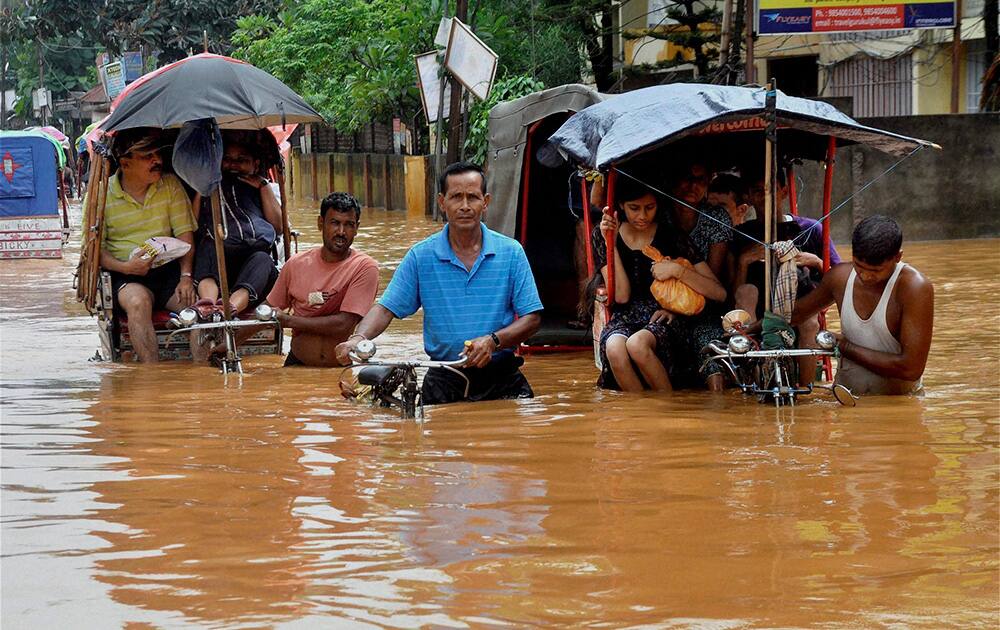 Rickshaw pullers wade through a waterlogged street after heavy rains in Guwahati.