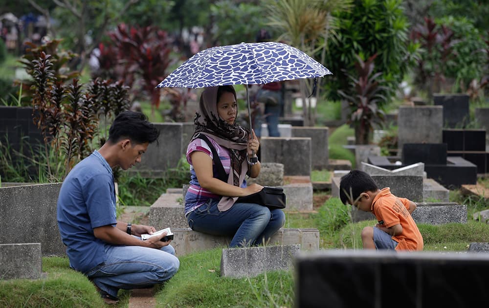 Indonesian family members pray at the grave of their relative at a cemetery in Jakarta, Indonesia. Prior to the holy fasting month of Ramadan that is expected to begin on Sunday.