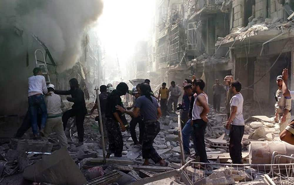 This photo provided by the anti-government activist group Syrian Observatory for Human Rights, which has been authenticated based on its contents and other AP reporting, shows Syrians inspect an area amid the rubble of destroyed buildings following a Syrian government airstrike at Karm al-Jabal area in Aleppo, Syria.