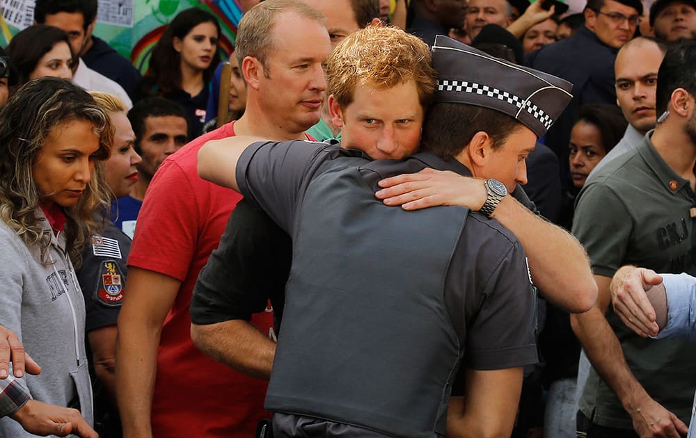 Britain`s Prince Harry hugs a police officer as he finishes his visit to a social project that aims to reduce drug addiction in an area known as `Crackland` in Sao Paulo, Brazil.