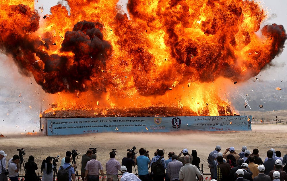 People look at a pile of seized narcotics is set fire during a ceremony commemorating International Day Against Drug Abuse and Illicit Trafficking in Tehran, Iran.