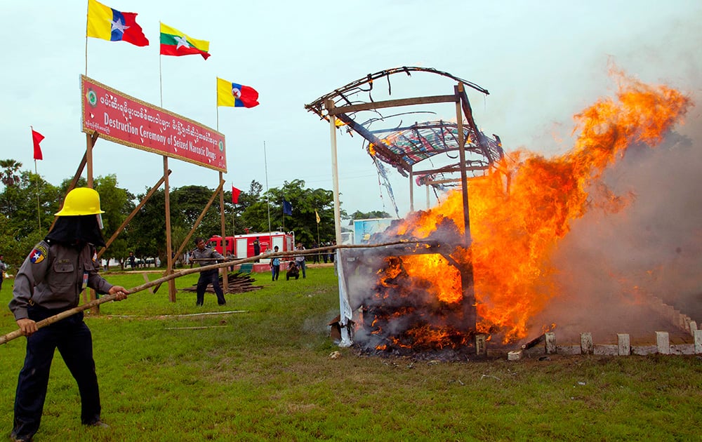 A Myanmar police officer jabs a stick to burning narcotic drugs during a destruction ceremony of seized narcotic drugs in outskirts of Yangon, Myanmar.