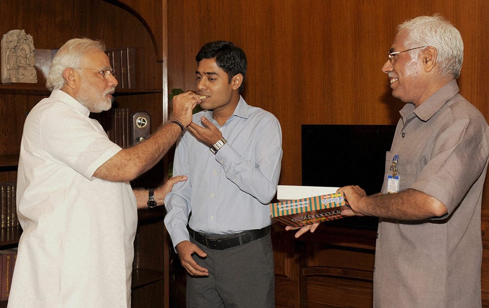 Prime Minister Narendra Modi greets the son of PMO staffer, Rajesh Kumar with sweets after he cleared the civil services examination in New Delhi.