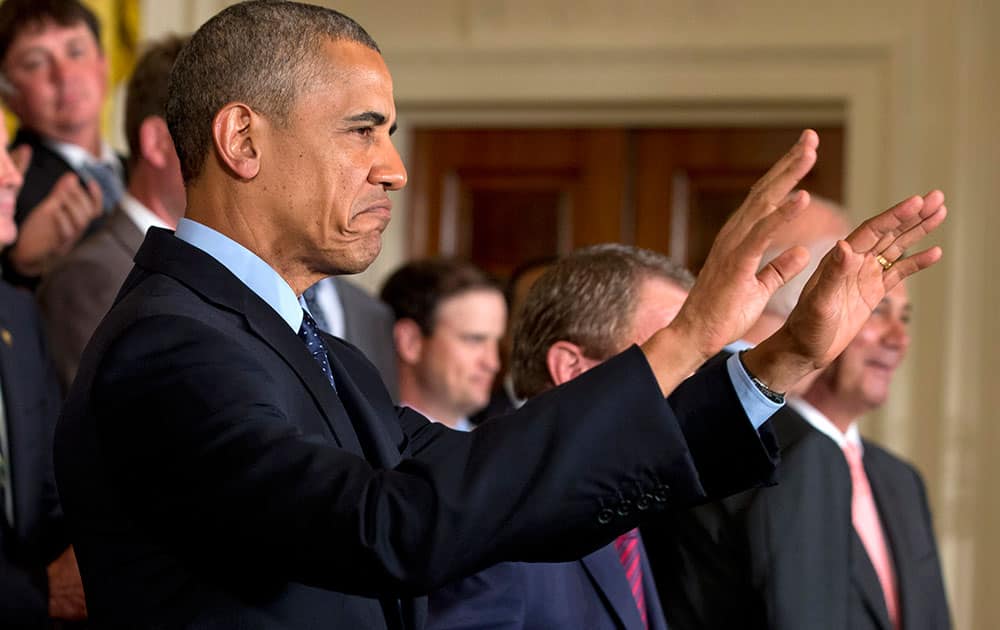 President Barack Obama gestures for the crowd to sit down before speaking at a ceremony honoring the 2013 Presidents Cup U.S. team during a ceremony in the East Room of the White House.